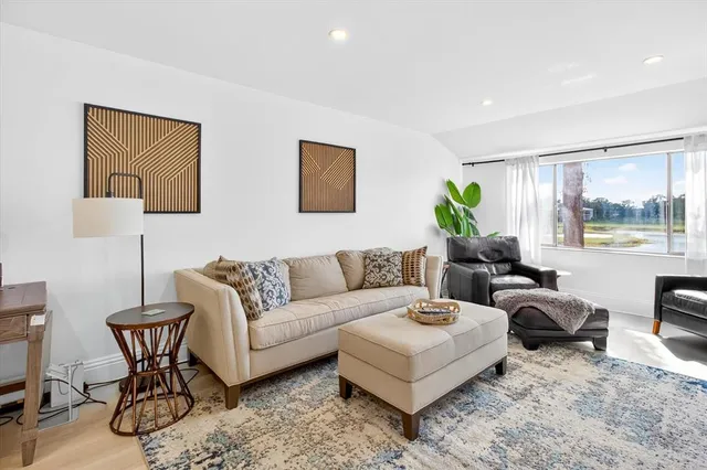 a living room with furniture wooden floor and a large window