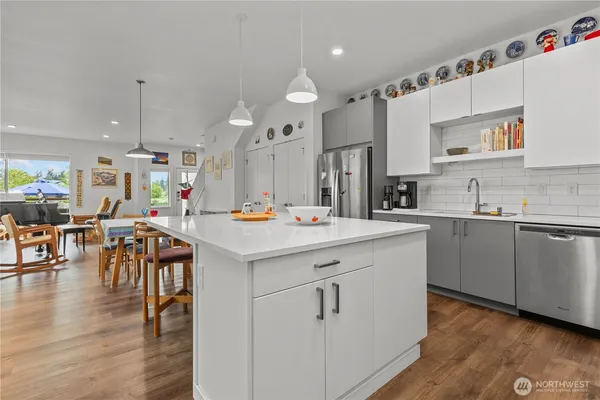 a kitchen with stainless steel appliances kitchen island wooden floors and white cabinets
