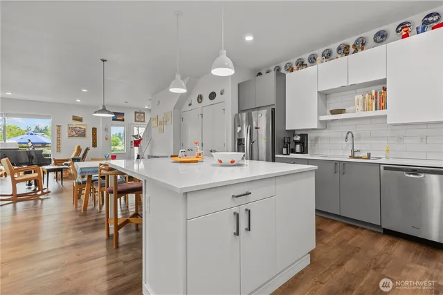 a kitchen with stainless steel appliances kitchen island wooden floors and white cabinets