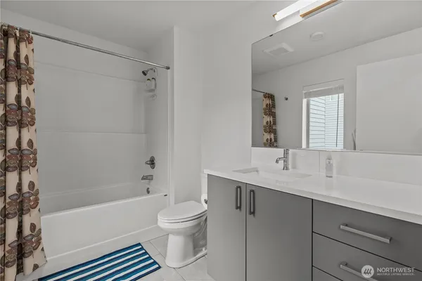 a bathroom with a bathtub shower sink vanity mirror and toilet