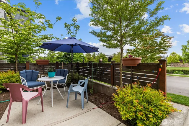 a view of a chairs and table under an umbrella in backyard