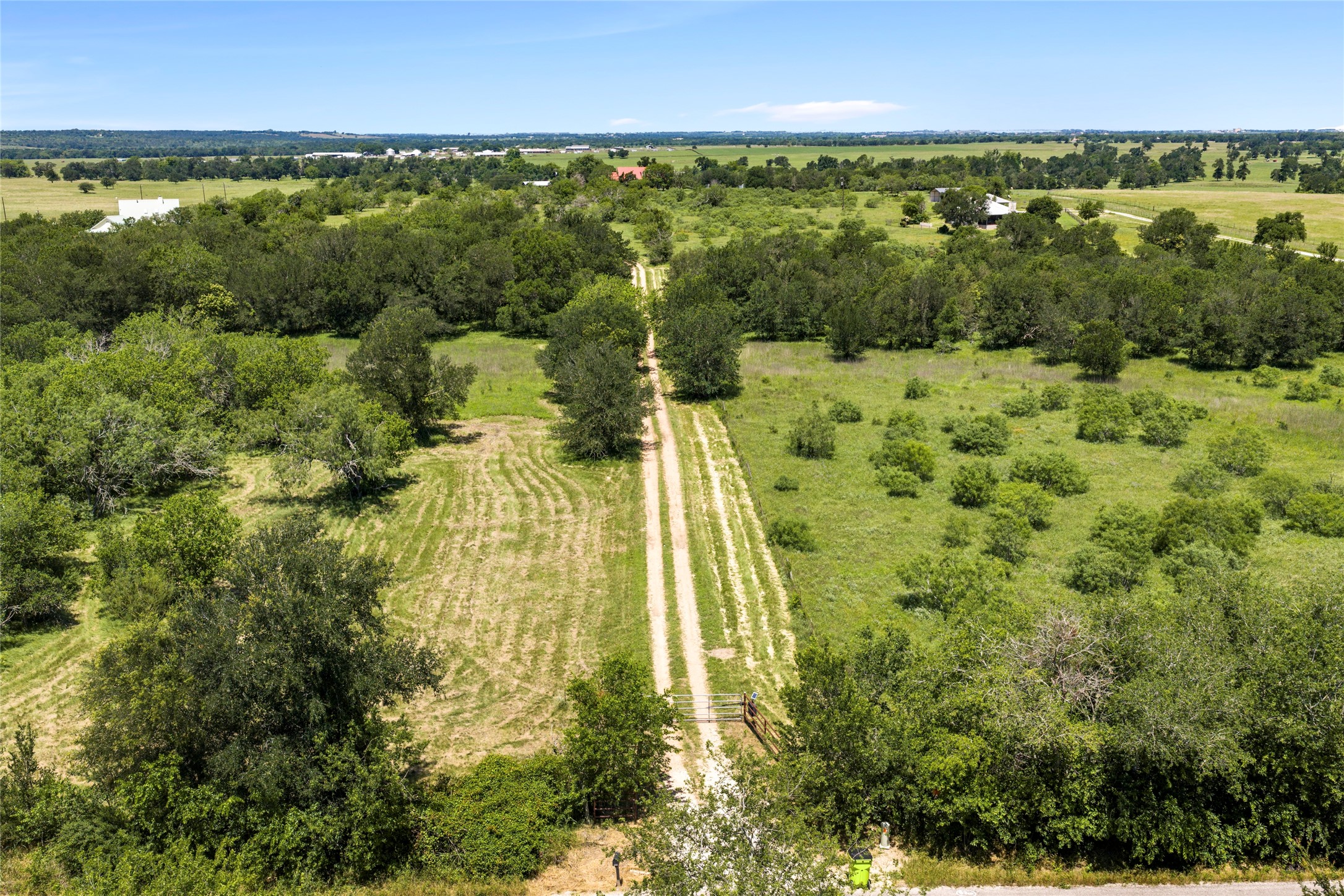 928 Upper Elgin River Road Elgin, TX 78621 - Photo 35 of 40 Expansive rural landscape featuring a long unpaved driveway, mature trees, & open grassy areas