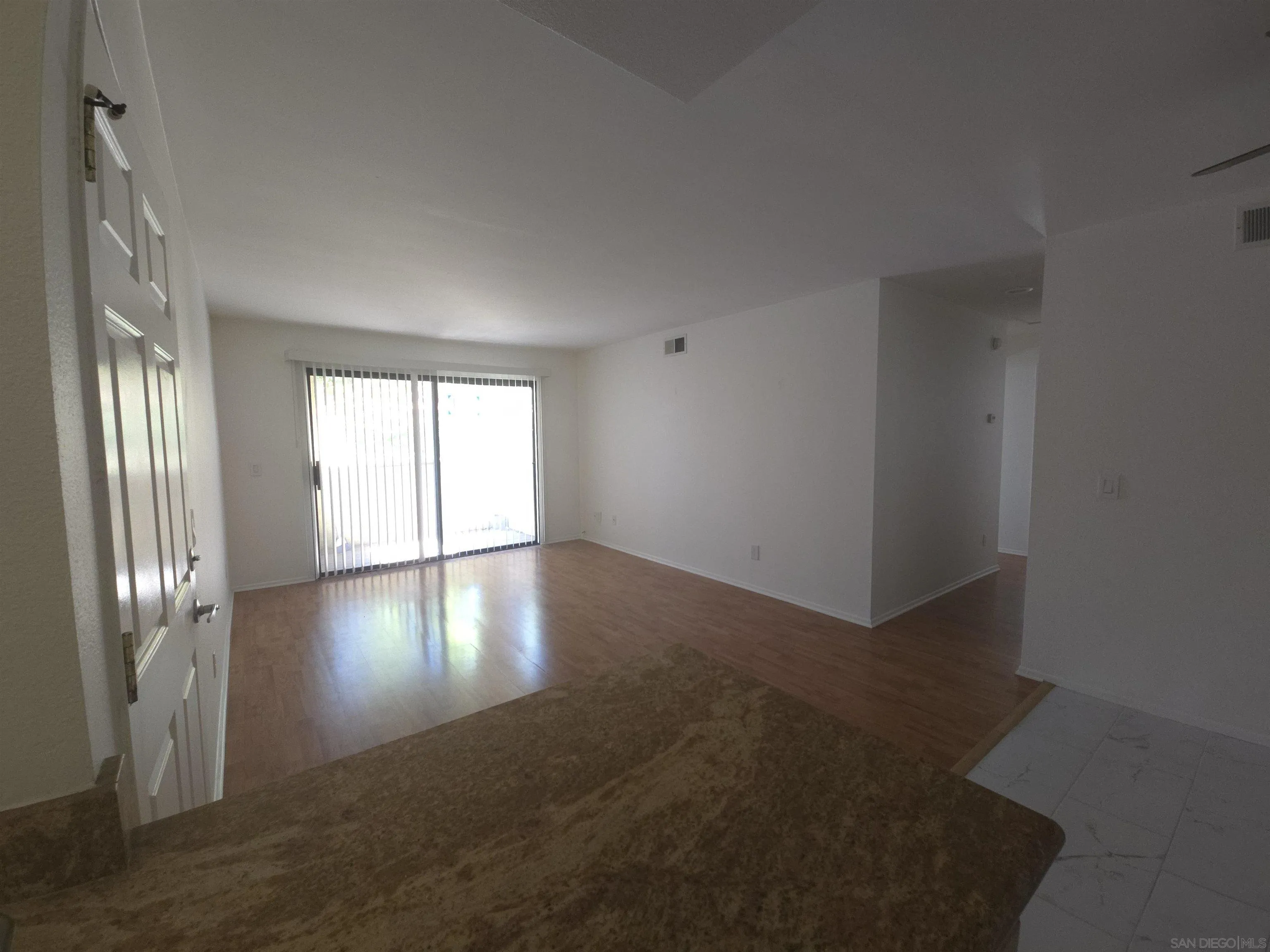 1130 West Blaine Street, Unit 204 Riverside, CA 92507 - Photo 6 of 24 an empty room with wooden floor and windows with curtains