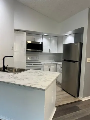 a kitchen with stainless steel appliances granite countertop a refrigerator a stove and a sink with wooden floor