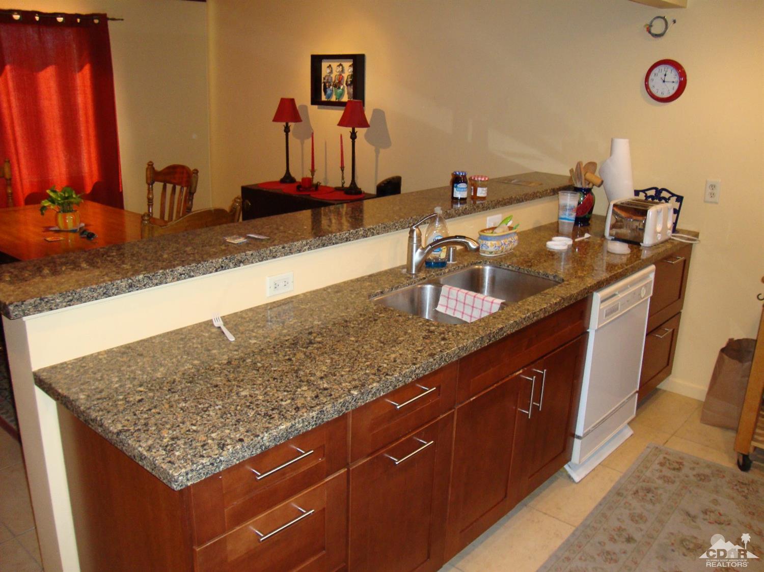 66671 San Rafael Road Desert Hot Springs, CA 92240 - Photo 11 of 36 a kitchen with kitchen island granite countertop a sink a counter top space and cabinets