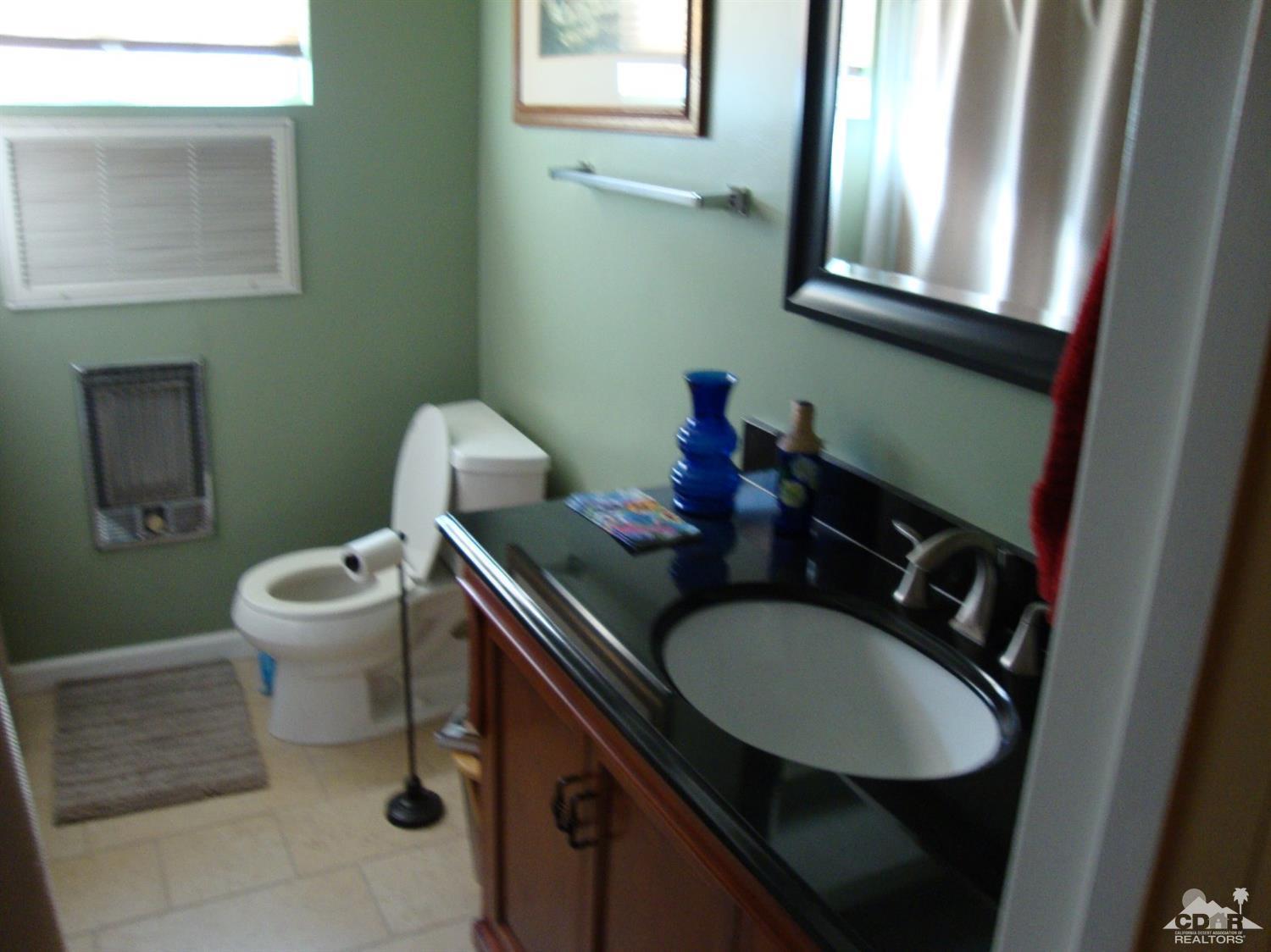 66671 San Rafael Road Desert Hot Springs, CA 92240 - Photo 17 of 36 a bathroom with a sink a toilet and a mirror
