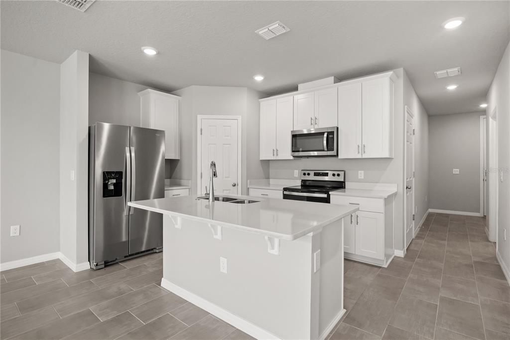 431 Legacy Loop Davenport, FL 33896 - Photo 6 of 25 a kitchen with kitchen island a refrigerator sink and microwave