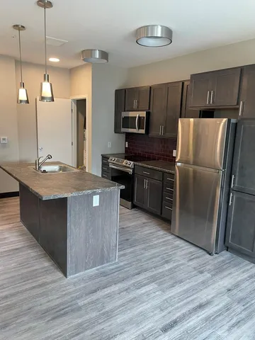 a kitchen with stainless steel appliances granite countertop a stove a refrigerator a sink and a oven