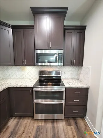 a kitchen with granite countertop wood cabinets and stainless steel appliances