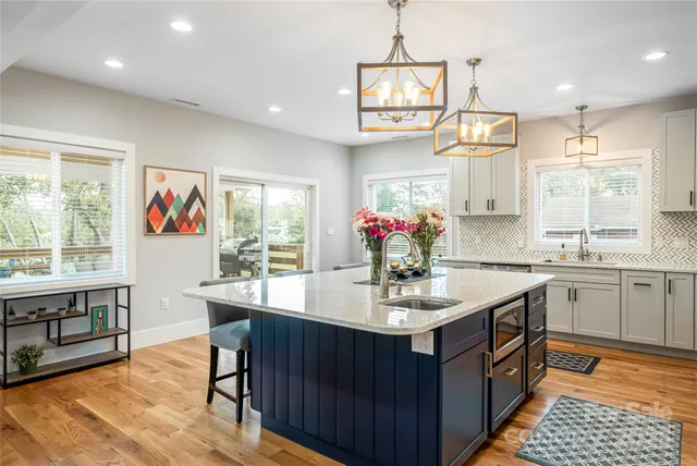 a kitchen with stainless steel appliances kitchen island granite countertop a sink dishwasher a dining table and chairs with wooden floor