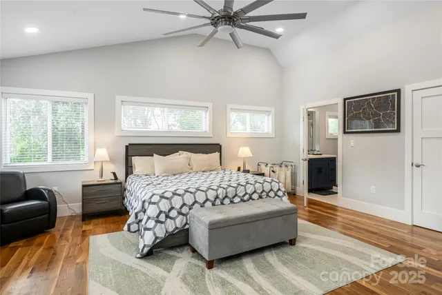 a bedroom with a bed couch and windows