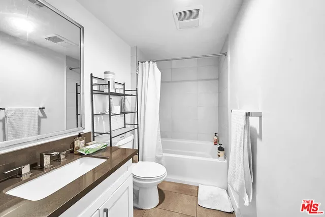 a bathroom with a bathtub shower sink vanity mirror and toilet