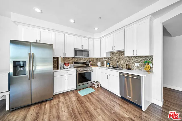 a kitchen with cabinets stainless steel appliances and wooden floor