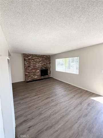 an empty room with wooden floor fireplace and windows