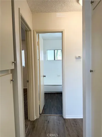 a view of a hallway with wooden floor and a bathroom