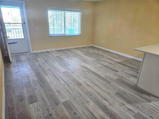 a view of kitchen with stainless steel appliances wooden floor and window
