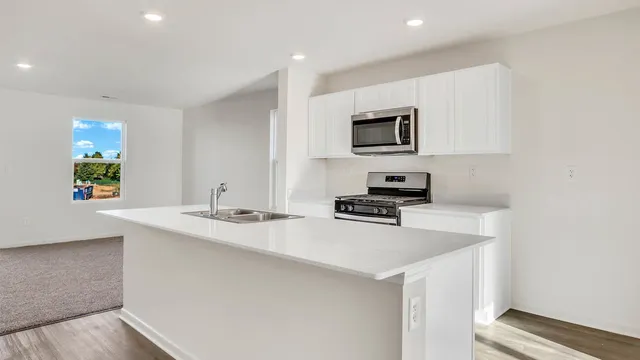 a kitchen with stainless steel appliances a stove top oven a sink a counter top space and cabinets