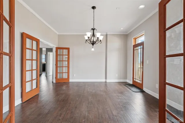 a view of a room with wooden floor chandelier and windows