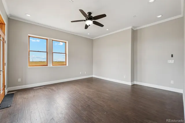 an empty room with wooden floor ceiling fan and windows