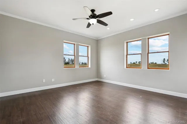 a view of an empty room with wooden floor and windows