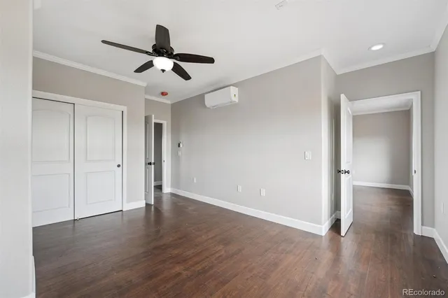 a view of an empty room with wooden floor and a ceiling fan