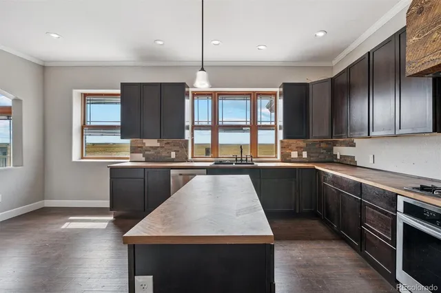 a kitchen with kitchen island granite countertop wooden cabinets a counter top space a sink and appliances