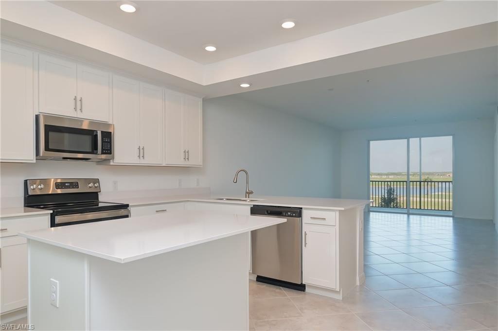 5835 Double Eagle Circle, Unit 4724 Immokalee, FL 34142 - Photo 7 of 25 a kitchen with a sink a stove a microwave and wooden floor