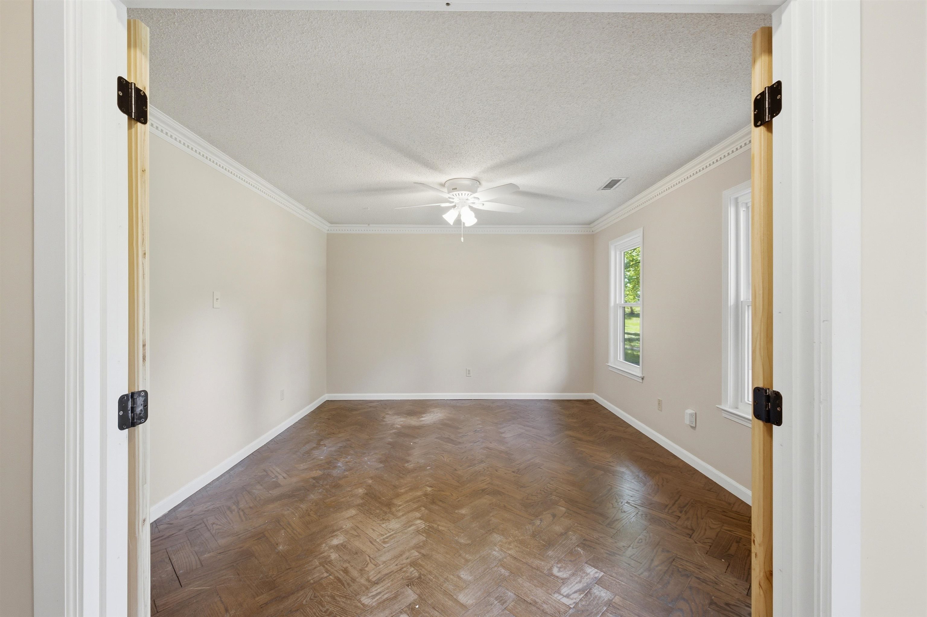 1370 North Reid Hooker Road Eads, TN 38028 - Photo 15 of 39 Spacious room featuring wood-finish flooring in a herringbone pattern, crown molding, and two windows providing natural illumination