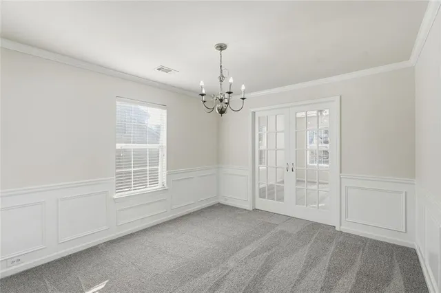an empty room with chandelier fan and windows
