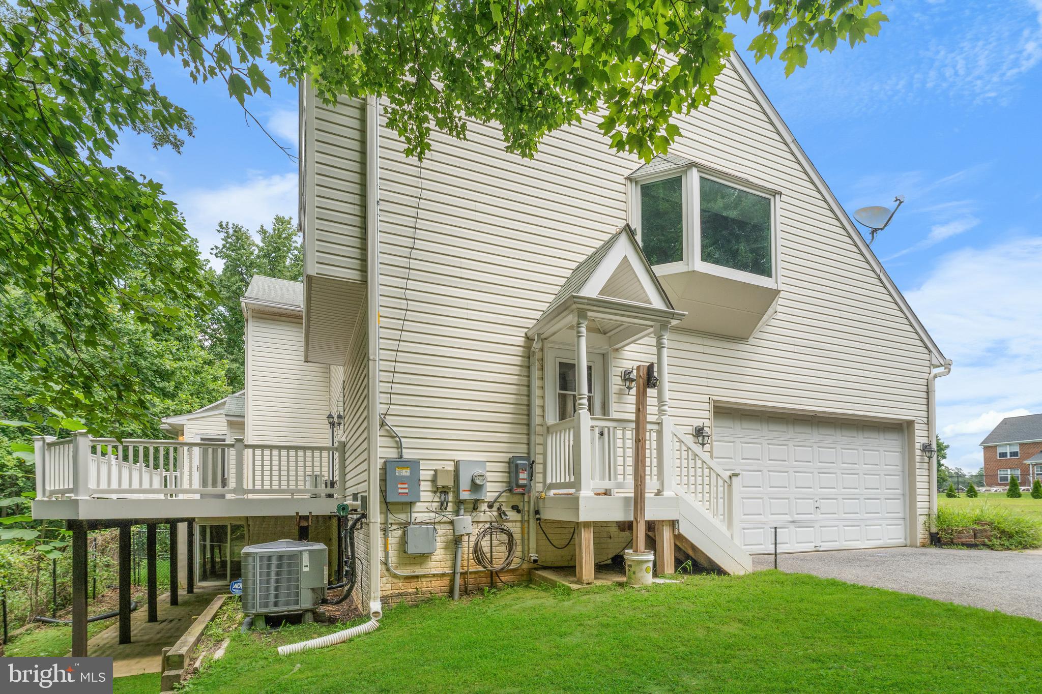 11709 Thrift Road Clinton, MD 20735 - Photo 6 of 71 a view of a white house next to a yard with plants and large trees