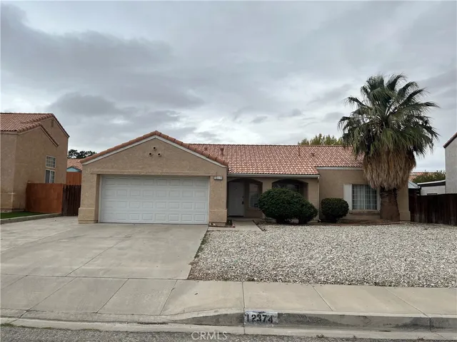 a front view of a house with garage and plants