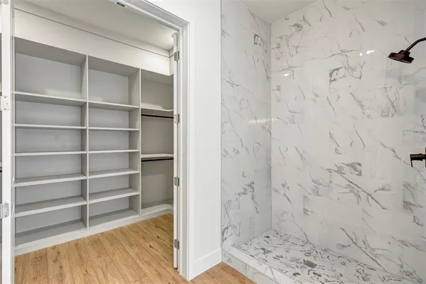 a walk in closet with wooden floor