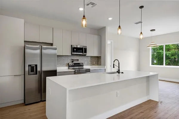 a kitchen with kitchen island a sink stainless steel appliances and window