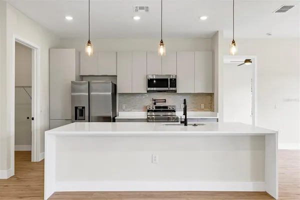 a kitchen with stainless steel appliances kitchen island a refrigerator and a stove top oven with wooden floor