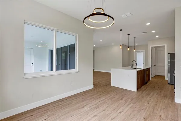 a view of kitchen with stainless steel appliances granite countertop a stove top oven a refrigerator and a dining table with wooden floor