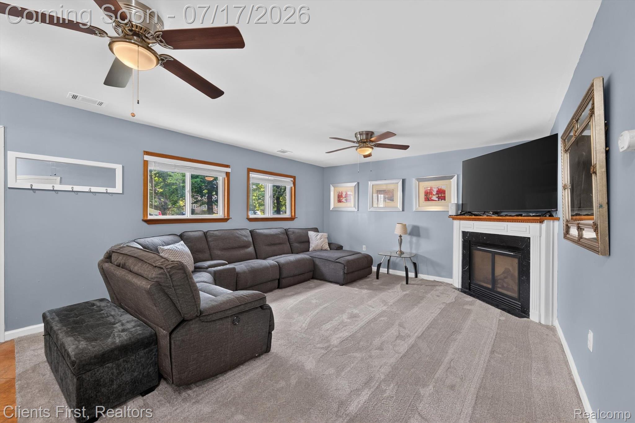 36852 Chase Street Romulus, MI 48174 - Photo 5 of 40 Living area featuring light gray carpeting, multiple windows with wood trim, and a fireplace with a white mantel and black surround