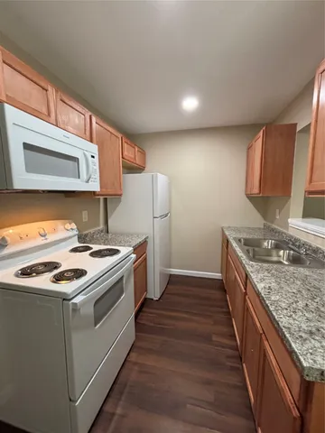 a view of a hallway with wooden floor and a bathroom