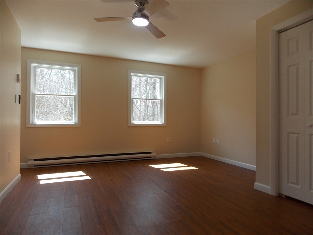 196 Main Street, Unit A Rockport, MA 01966 - Photo 19 of 36 an empty room with wooden floor and windows
