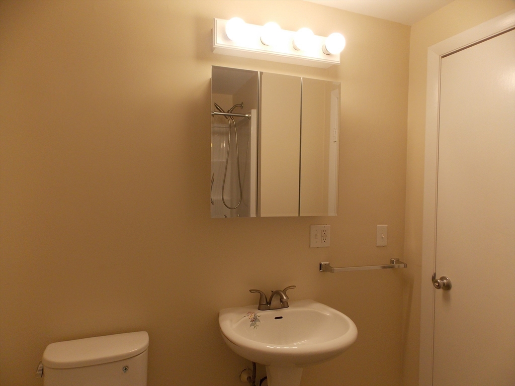 196 Main Street, Unit A Rockport, MA 01966 - Photo 27 of 36 a bathroom with a sink a toilet and mirror