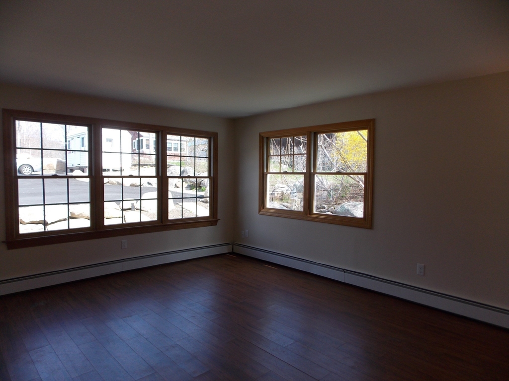 196 Main Street, Unit A Rockport, MA 01966 - Photo 3 of 36 an empty room with wooden floor and windows