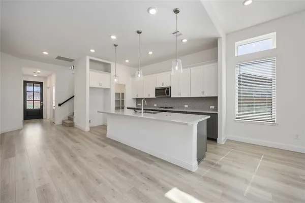 a kitchen with stainless steel appliances granite countertop a stove a sink a refrigerator and white cabinets with wooden floor