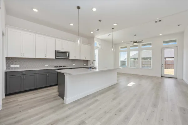 a large kitchen with stainless steel appliances granite countertop a stove a sink and white cabinets with wooden floor