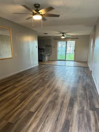 an empty room with wooden floor closet and windows