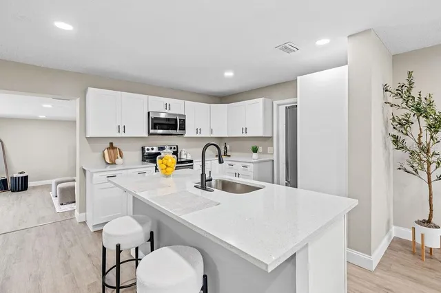 a kitchen with a sink a stove a refrigerator cabinets and a dining table with wooden floor