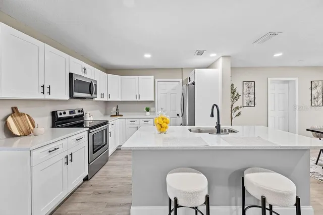 a kitchen with stainless steel appliances granite countertop a sink a stove a refrigerator cabinets and chairs