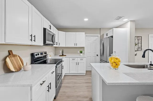 a kitchen with stainless steel appliances granite countertop a sink dishwasher stove and refrigerator with wooden cabinets