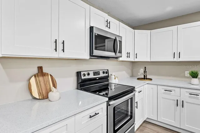 a kitchen with stainless steel appliances granite countertop a sink a stove and microwave with wooden floor