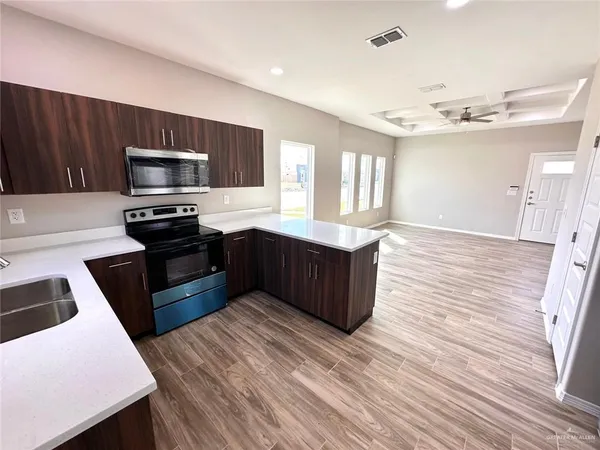 a kitchen with stainless steel appliances a sink dishwasher a stove top oven a refrigerator with wooden floors and cabinets