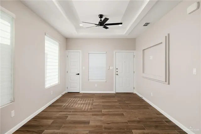 a view of empty room with wooden floor and fan