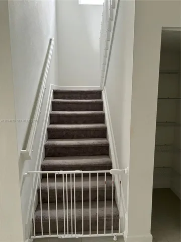 a view of staircase with railing and white walls